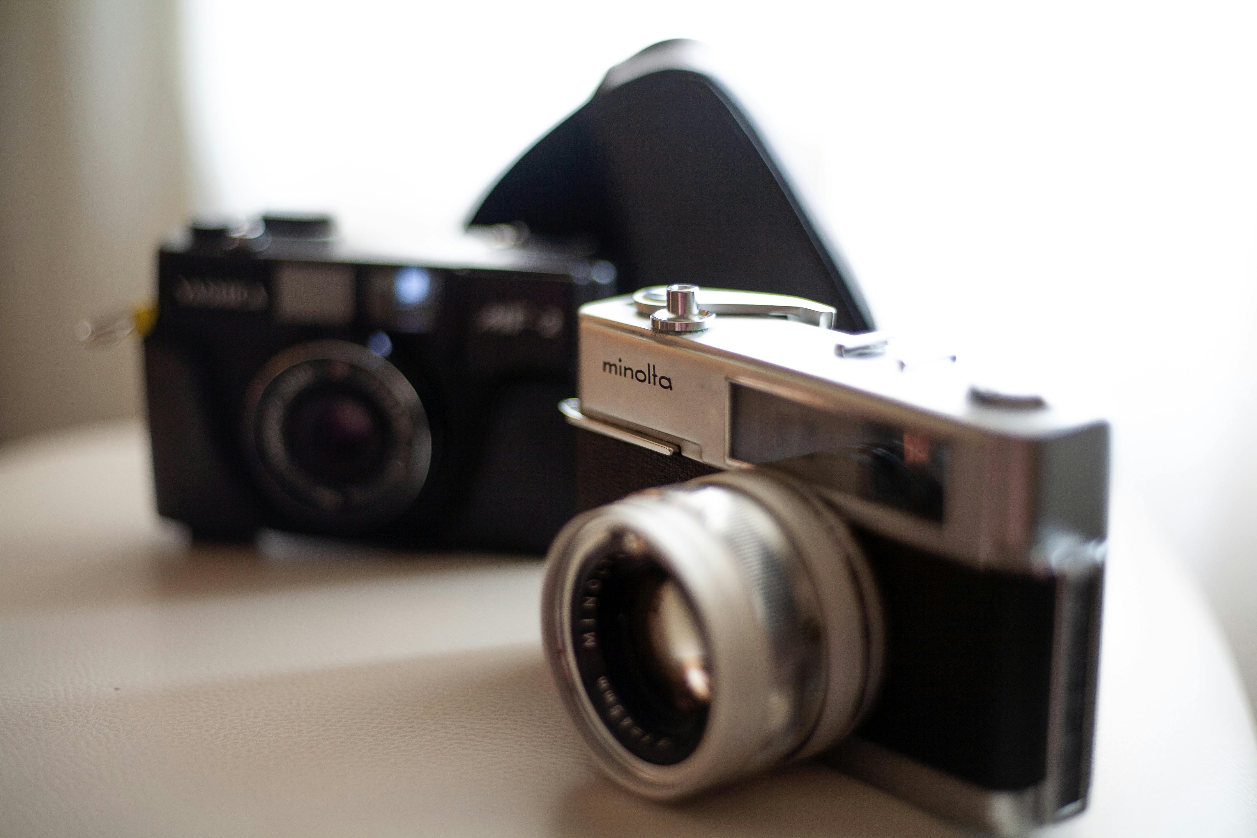 Close-up of vintage Minolta and Yashica film cameras on a neutral background.